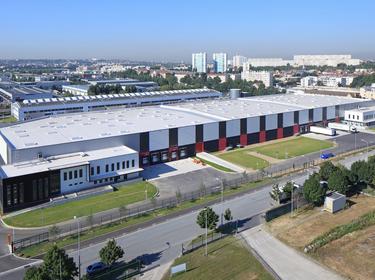 Aerial exterior view of Prologis Bonneuil Distribution Center 1 in France, red, black and white accents on the building with fields and trees surrounding.